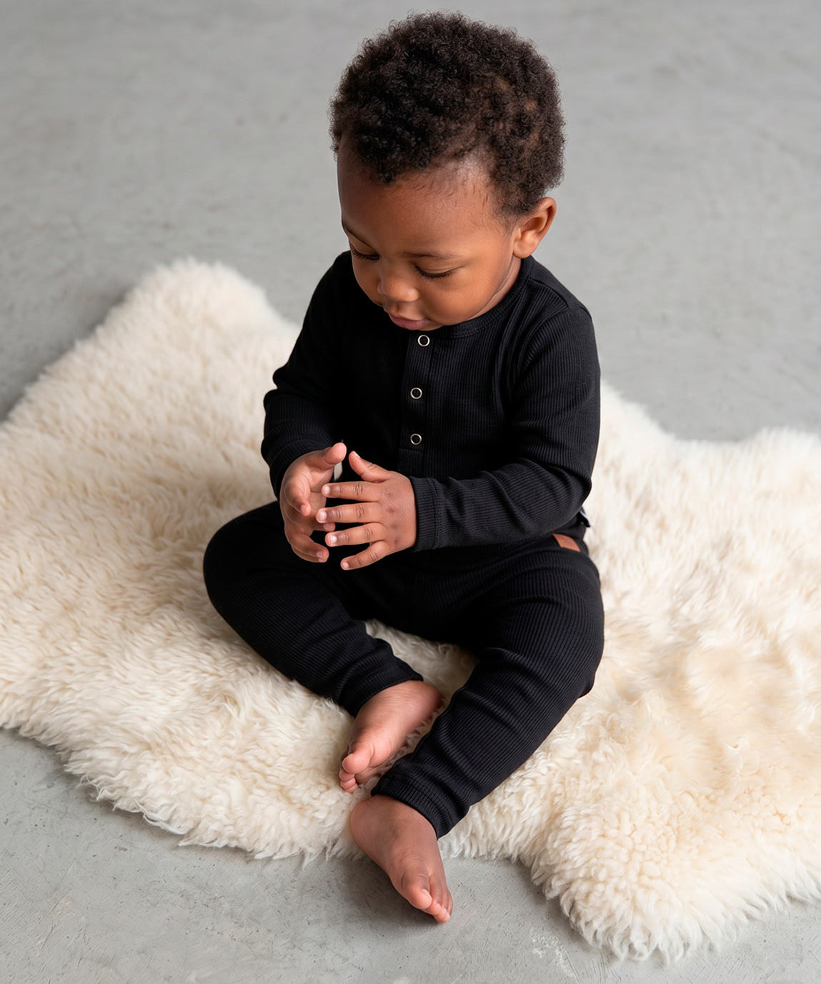 Calça Slim Canelada Bebê Liso Preto MiniMalista — cós elástico wide sem cadarço, etiqueta de couro caramelo no hip, malha canelada tom Preto 100% algodão fitted no corpinho.