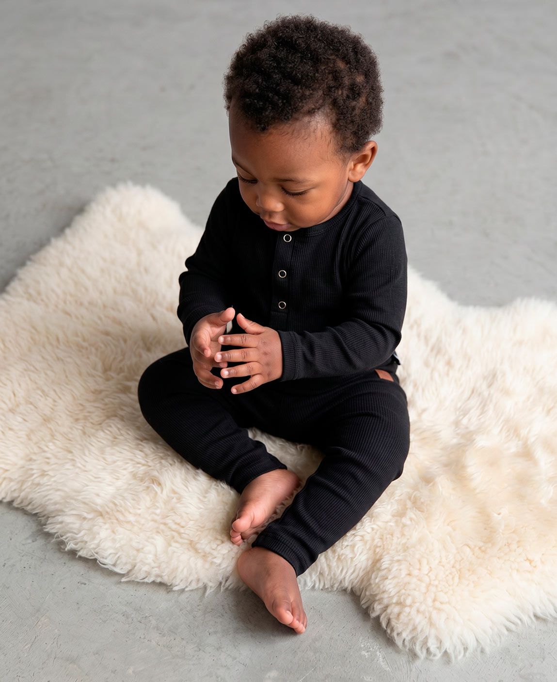 Calça Slim Canelada Bebê Liso Preto MiniMalista — cós elástico wide sem cadarço, etiqueta de couro caramelo no hip, malha canelada tom Preto 100% algodão fitted no corpinho.