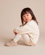 MiniMalista Conjunto Moletom + Calça Canelada Liso Branco Off vestido em criança. Look all-white elegante infantil 100% algodão, moletom peluciado e calça canelada slim no mesmo tom, conjunto unissex menino e menina.