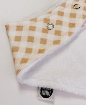 Detalhe do xadrez vichy bege e da malha de algodão do Babador Bandana MiniMalista. Babador de bebê unissex, estampa atóxica, acabamento macio.