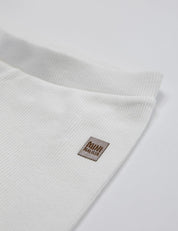 Calça Canelada Slim Liso Branco Off MiniMalista vista lateral — calça infantil 100% algodão em ribana elástica, look minimalista escandinavo all-white para bebê e criança unissex, base coringa do guarda-roupa.