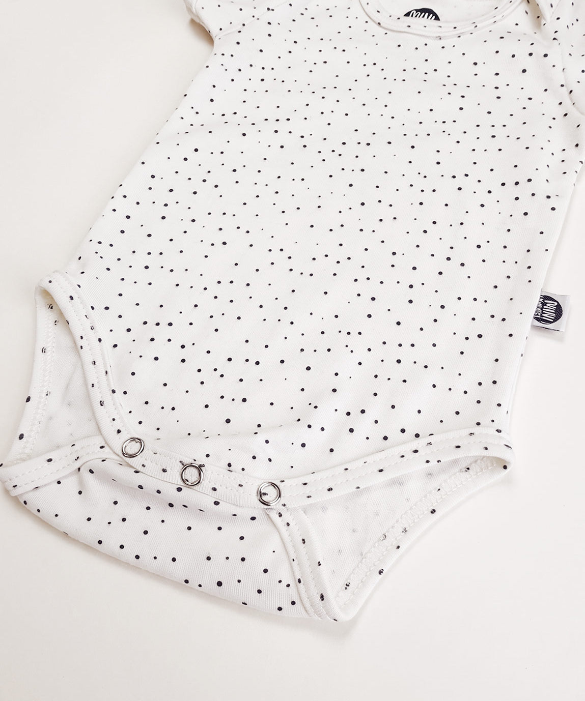 Detalhe das bolinhas delicadas e da malha de algodão do Body Manga Curta Bolinhas Claro MiniMalista. Body de bebê unissex, estampa atóxica, acabamento macio.
