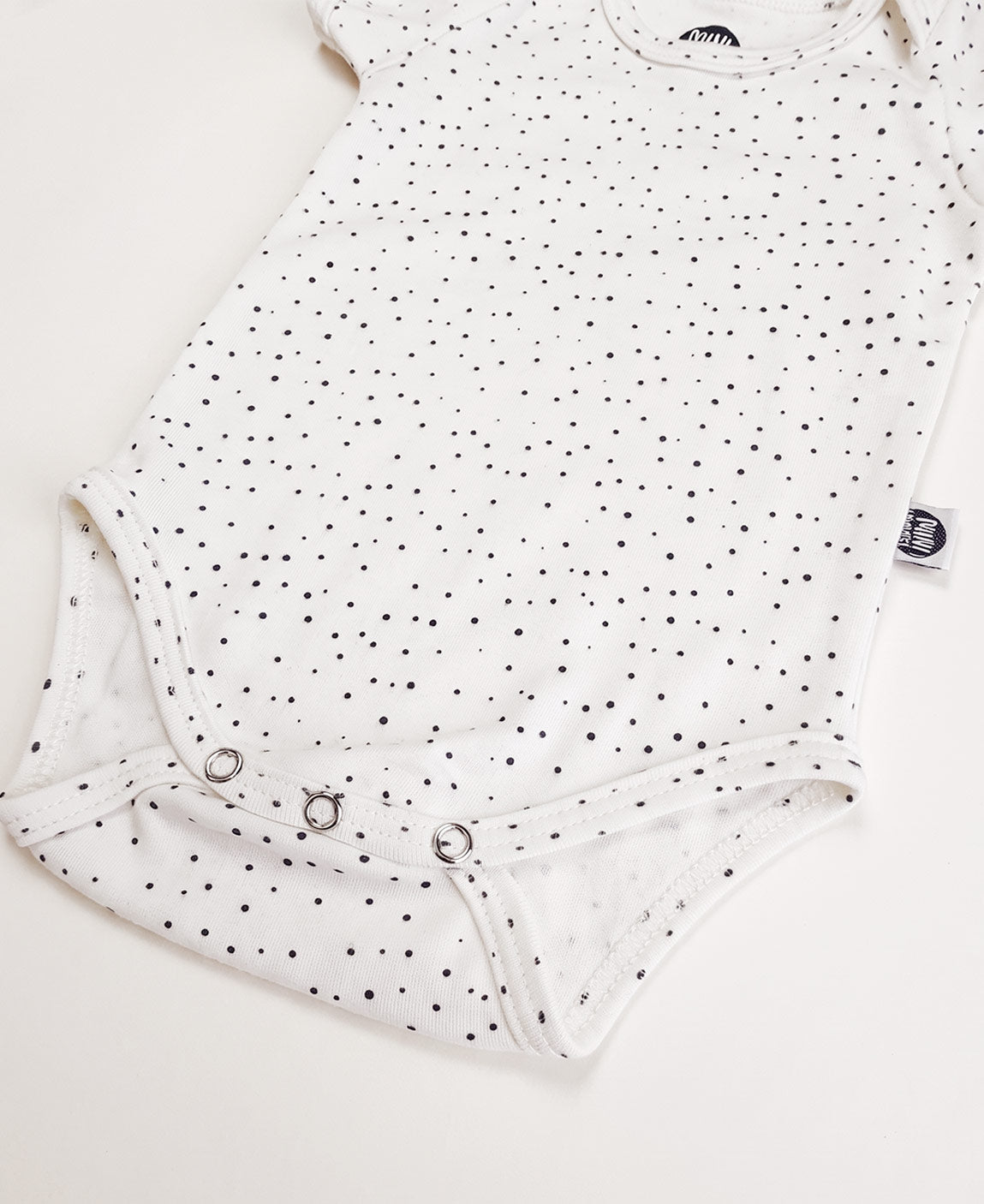 Detalhe das bolinhas delicadas e da malha de algodão do Body Manga Curta Bolinhas Claro MiniMalista. Body de bebê unissex, estampa atóxica, acabamento macio.