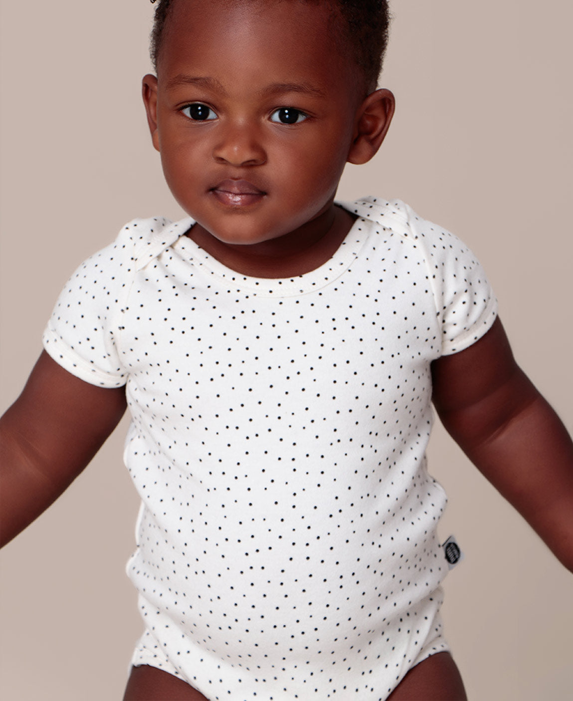 Bebê sorrindo vestindo o Body Manga Curta Bolinhas Claro MiniMalista. Body de bebê em algodão com poá delicado, unissex.